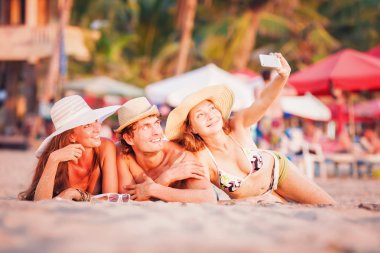 Gençlerin grup wite sahil kumu üzerinde yalan ve selfie fotoğraf çekme mutlu 