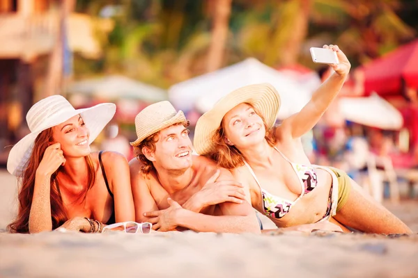 Grupp glada ungdomar ligga på wite sandstrand och ta selfie Foto — Stockfoto