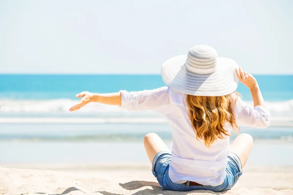 Gyönyörű fiatal nő ül a strandon a napsütéses napon Élvezi a nyári vakáció — Stock Fotó