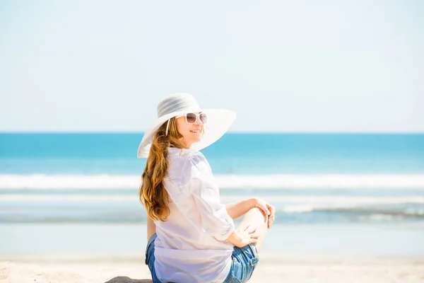 Beautifil Młoda kobieta siedzi na plaży w słoneczny dzień, ciesząc się wakacjami — Zdjęcie stockowe