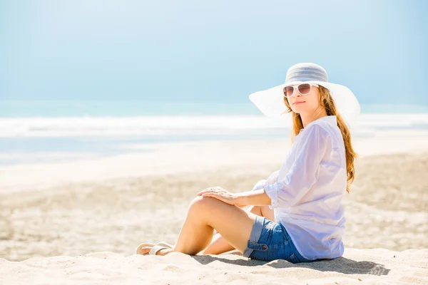 Beautifil Młoda kobieta siedzi na plaży w słoneczny dzień, ciesząc się wakacjami — Zdjęcie stockowe