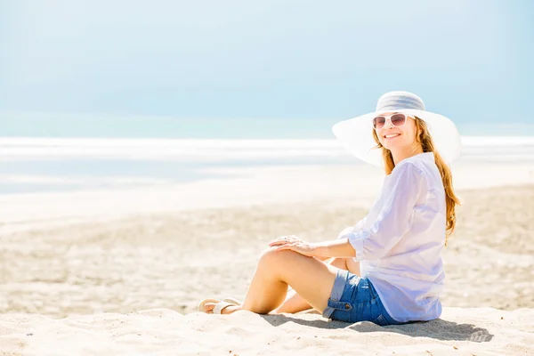 Beautifil jovem mulher sentada na praia no dia ensolarado desfrutando de férias de verão — Fotografia de Stock