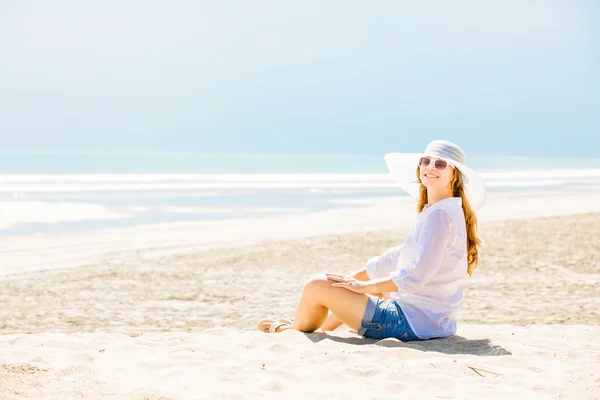 Beautifil Młoda kobieta siedzi na plaży w słoneczny dzień, ciesząc się wakacjami — Zdjęcie stockowe