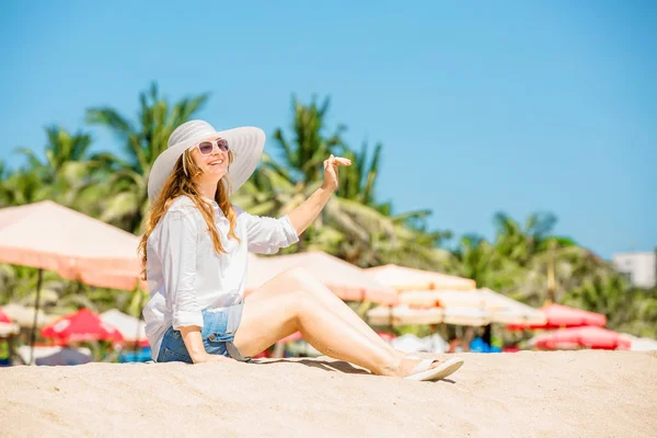 Beautifil Młoda kobieta siedzi na plaży w słoneczny dzień, ciesząc się wakacjami — Zdjęcie stockowe