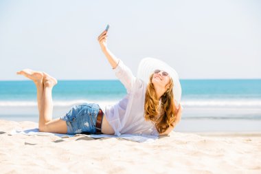 Sahilde güneşli gün ve alma selfie telefon ile yalan Beautifil genç kadın