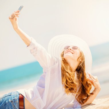 Sahilde güneşli gün ve alma selfie telefon ile yalan Beautifil genç kadın
