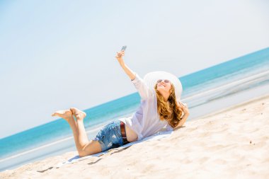 Sahilde güneşli gün ve alma selfie telefon ile yalan Beautifil genç kadın