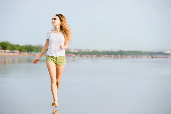 Молодая кавказка бежит по пляжу на закате — стоковое фото