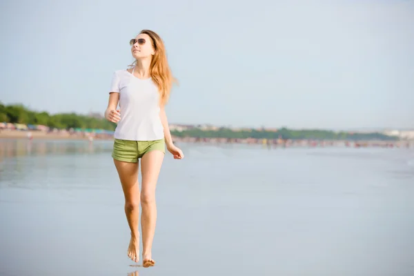 Caucasion młoda kobieta działa na plaży o zachodzie słońca — Zdjęcie stockowe