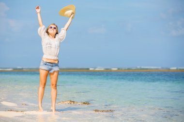 sıska beyaz kız plajda mavi gökyüzü ve saf okyanus su arka plan üzerinde beyaz şapka ile sallayarak. seyahat, tatil, cennet kavramı, boşaltmak