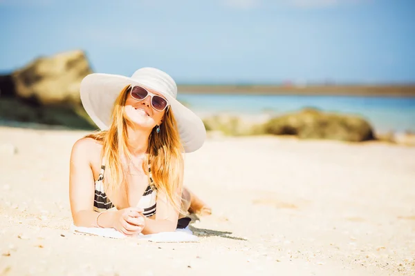 Chica rubia feliz sexual con gafas de sol y sombrero blanco tomar el sol en la playa disfrutando de las vacaciones de verano. Viajes, vacaciones, concepto de estilo de vida. Espacio de copia —  Fotos de Stock