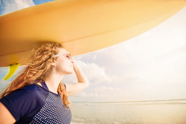 Belle jeune fille caucasienne en rushwest et lunettes de soleil avec planche de surf jaune à la plage légian, Bali. Lyfestyle, loisir, sport, vacances, happines concept — Photo