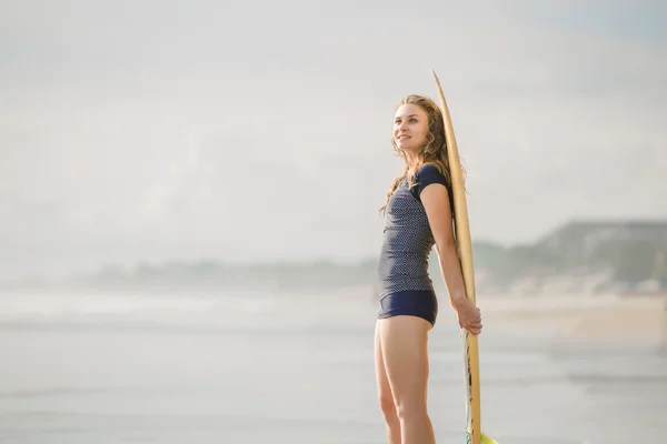 Belle jeune fille surfeuse reste sur la plage au coucher du soleil avec planche de surf jaune. Style de vie sain, loisirs, voyage, vacances et sport concept, copyspace — Photo