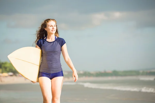 Сексуальная девушка-серфер на пляже на закате прогуливается вдоль берега океана, желтая доска для серфинга в руках. Здоровый образ жизни, спортивная концепция с копирайтом — стоковое фото