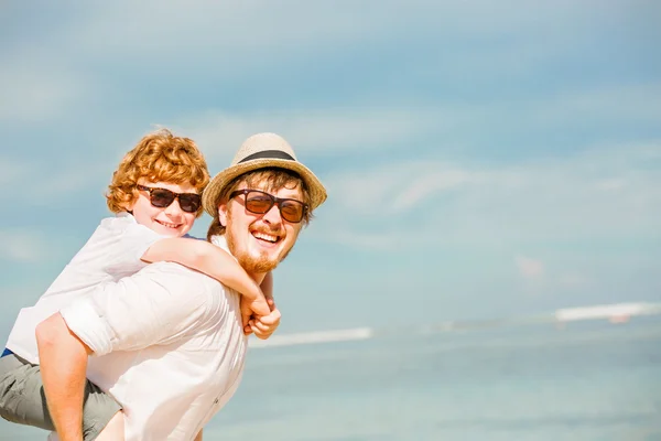 Hipster pai com barba e cabelo vermelho filho usando óculos de sol ter tempo de verão feliz em um dia ensolarado em férias. Família, felicidade, conceito de viagem — Fotografia de Stock
