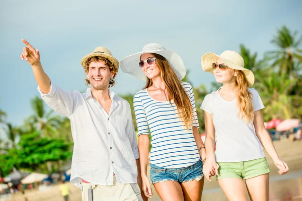 Група щасливих молодих людей, що гуляють вздовж пляжу на красивому літньому заході сонця — стокове фото