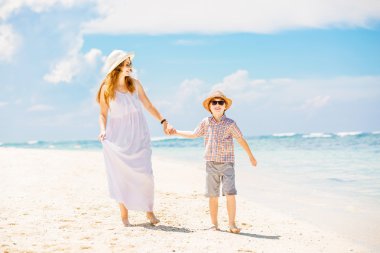 Mother and son walk along the white sand beach having great family holidays time on PAndawa beach, Bali