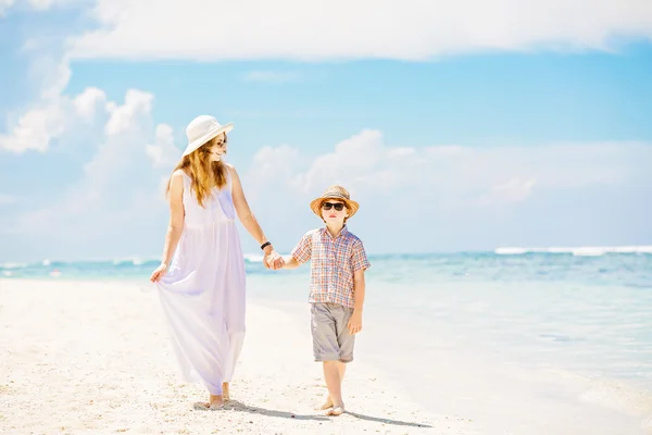 Mother and son walk along the white sand beach having great family holidays time on PAndawa beach, Bali