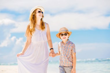 Mother and son walk along the white sand beach having great family holidays time on PAndawa beach, Bali