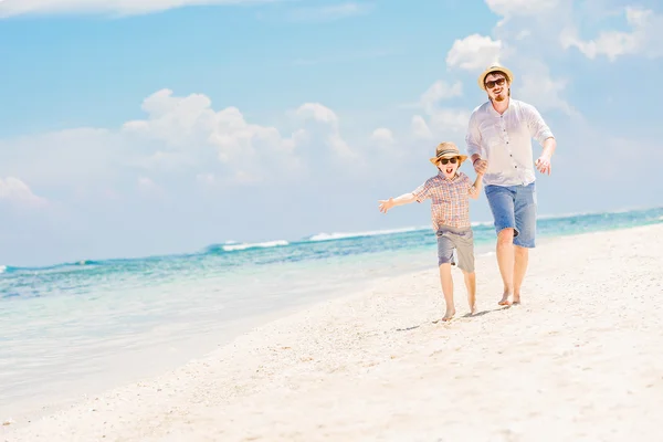 Father with son running barefoot on the sea surf line having great holidays time — Stok fotoğraf