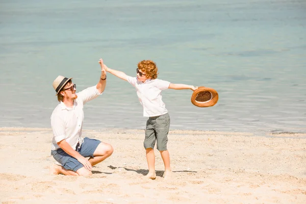 Hipster ojca z brodą i czerwone włosy syn gra na plaży w słoneczny dzień. pojęcie przyjazny rodzinie — Zdjęcie stockowe