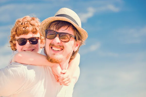 Hipster father with beard and red haired son having happy summer time at a sunny day. Concept of friendly family