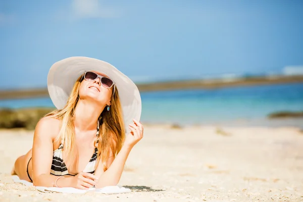 Sexual happy blond girl with sunglasses and white hat take sunbath on the beach enjoying summer holidays. Travel, vacation, lifestyle concept. Copyspace — Stock Photo, Image