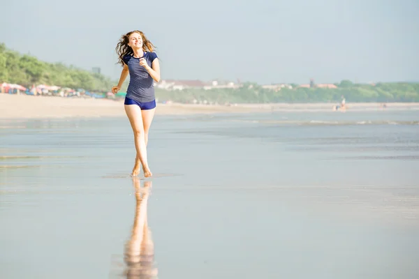 Young beautiful caucasion woman with brown hair runs along the beach on Bali close to sunset — Stock fotografie