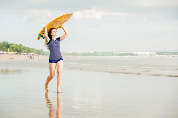 Mooie sexy surfer meisje op het strand bij zonsondergang wandelingen langs Oceaan kust, gele surfplank in haar handen. gezond leven, sport concept met copyspace — Stockfoto