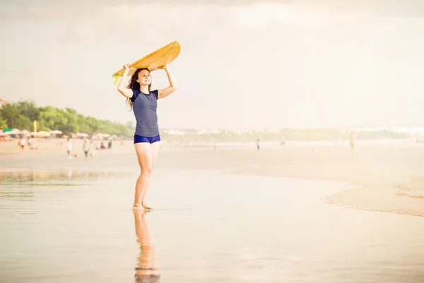 Mooie sexy surfer meisje op het strand bij zonsondergang wandelingen langs Oceaan kust, gele surfplank in haar handen. gezond leven, sport concept met copyspace — Stockfoto