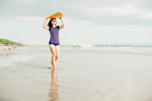 Bella ragazza surfista sexy sulla spiaggia al tramonto passeggiate lungo la riva dell'oceano, tavola da surf gialla nelle sue mani. Vita sana, concetto di sport con copyspace — Foto Stock