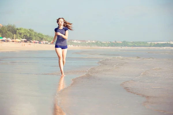 Gezonde vrouw draait op het strand, meisje sport buiten doen, gelukkig vrouw uit te oefenen, fitness en heide zorg concept met kopie ruimte over natuurlijke warm zonsondergang achtergrond — Stockfoto