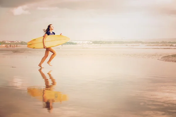 Beautiful sexy surfer girl on the beach at sunset running into ocean, yellow surfboard in her hands. Healthy life, sport  concept with copyspace — Stock Photo, Image