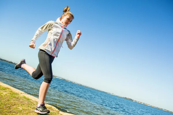 Young woman running near the river at sunny day. Sportswoman exercise — Stock Photo, Image