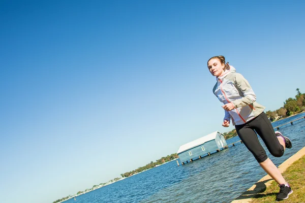Young woman running near the river at sunny day. Sportswoman exercise — Stock Photo, Image