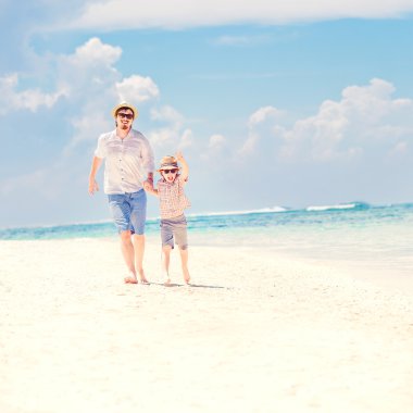 Father with son running barefoot on the sea surf line having great holidays time