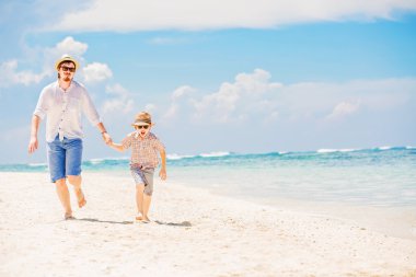 Father with son running barefoot on the sea surf line having great holidays time
