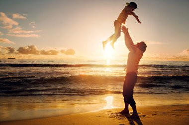 Father and son having fun together in sunset ocean on summer holidays