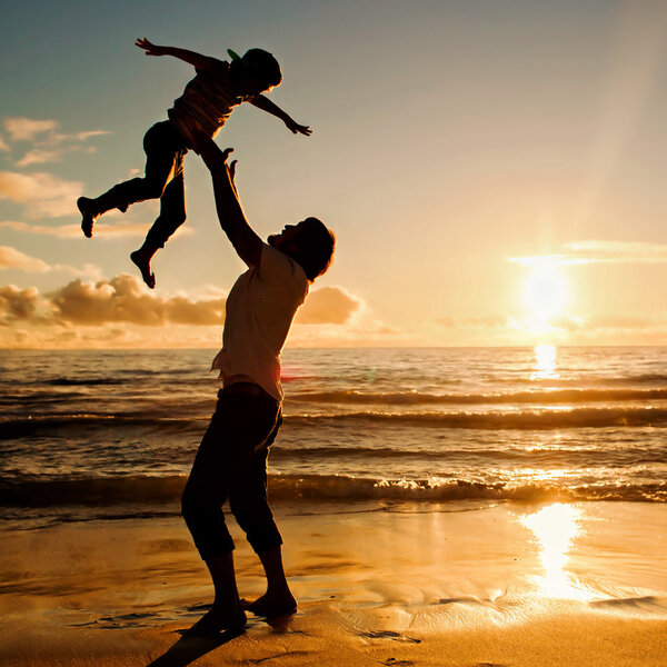 Father and son having fun together in sunset ocean on summer holidays