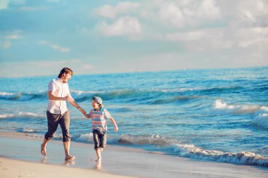 Father and son having great family time at ocean shore on summer holidays