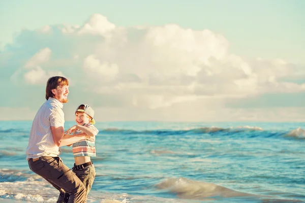 Père et fils s'amusent ensemble au coucher du soleil sur l'océan pendant les vacances d'été — Photo