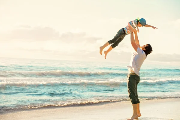 Padre e hijo se divierten juntos en el océano al atardecer en vacaciones de verano — Foto de Stock