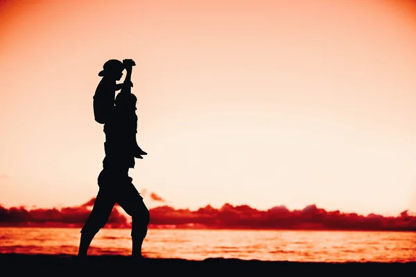 Siluetas de padre e hijo divirtiéndose juntos al atardecer en vacaciones de verano —  Fotos de Stock