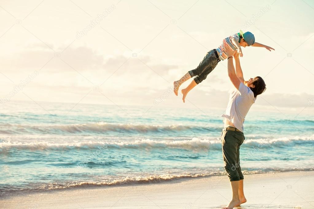 Father and son having fun together in sunset ocean on summer holidays