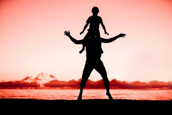 Silhouette di padre e figlio che si divertono insieme al tramonto durante le vacanze estive — Foto Stock