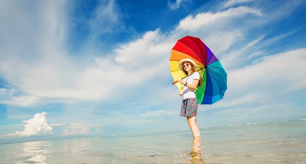 Wesoły młoda dziewczyna z tęczy parasol zabawy na plaży — Zdjęcie stockowe
