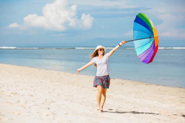 Joyeux jeune fille avec parapluie arc-en-ciel s'amuser sur la plage — Photo