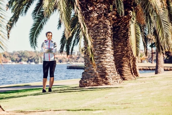 Mode de vie sain jeune femme sportive ayant une pause entre les palmiers après avoir fait du jogging au parc tropical — Photo