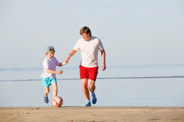 Mutlu baba ve oğul plaj futbol ya da futbol oynamak