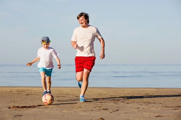 Šťastný otec a syn hrát fotbal nebo fotbal na pláži — Stock fotografie
